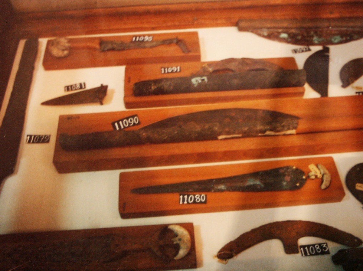 Collection of ancient Egyptian bronze weapons and artefacts in a museum display case